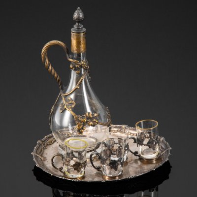 купить Набор для крепких напитков, состоящий из подноса, графина и четырех стопок на подставках, с растительным декором и дарственной надписью "Въ память отъ любящихъ дѣтей XXV" и "1883.20.10/1908", стекло, металл, серебрение, Plewkiewicz & Co. (Фабрика Романа Плевкевича), Царство Польское, 1908 г.