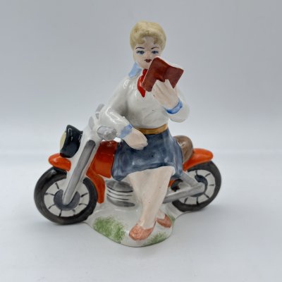 купить Статуэтка "Пионерка на мотоцикле с книгой", фарфор, роспись, Полонский завод художественной керамики (Полонное ЗХК), Украина, 1980-2000 гг.
