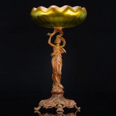 купить Фруктовница (ваза) в стиле модерн на фигурном основании в виде нимфы на шаре, которая держит чашу зеленоватого оттенка в виде раскрывающейся водяной лилии, loetz (?), металл, литье, формовка, стекло, гутная техника, иризация, Западная Европа, 1900-1920 гг.